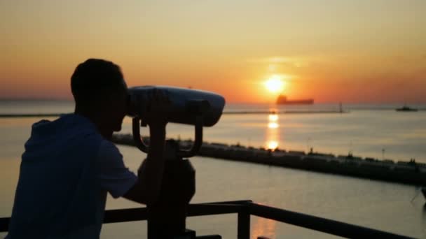 Silhueta homem olha em binocular e observa o pôr do sol âmbar — Vídeo de Stock