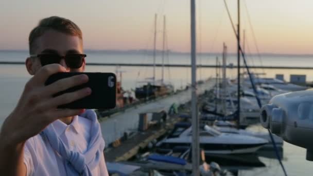 Uomo cammina lungo il lungomare e fa selfie contro gli yacht — Video Stock