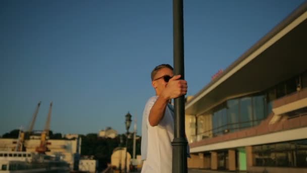 Man rent naar high street lamp en draait zich om glimlachend — Stockvideo