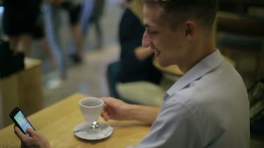 Adam bir fincan kahve içiyor ve internette sörf yapıyor.