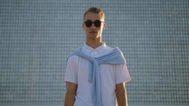 Serieus guy poses staande in de voorkant van glas stedelijk gebouw — Stockvideo