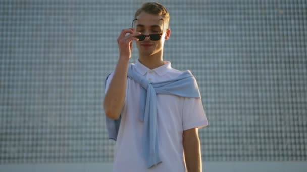 Mann setzt Sonnenbrille auf und posiert vor Hochhaus — Stockvideo