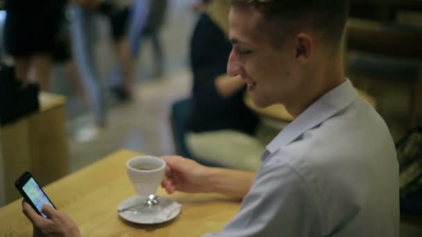 Hombre bebe taza de café y navega Internet sentado en la cafetería — Vídeo de stock