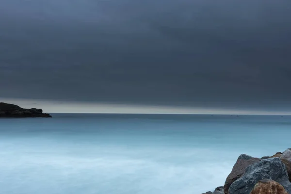 Una foto a lunga esposizione di una spiaggia con il cielo buio che sta per piovere — Foto Stock