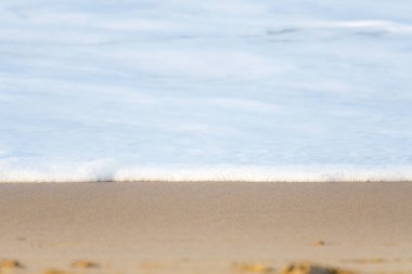 Kumlu sahile ulaşan bir dalganın köpüğü