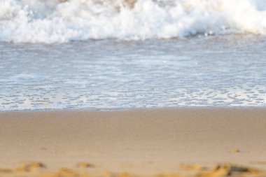 Kumlu sahile ulaşan bir dalganın köpüğü