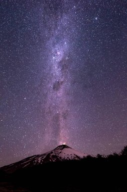 Şili 'deki Villarrica Volkanı' nın üzerinde Samanyolu ile gökyüzünde binlerce yıldız, dikey fotoğraf