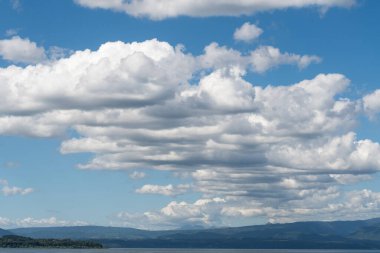 Mavi gökyüzü ve bazı dağlar arasında neredeyse simetrik bir grup beyaz bulut