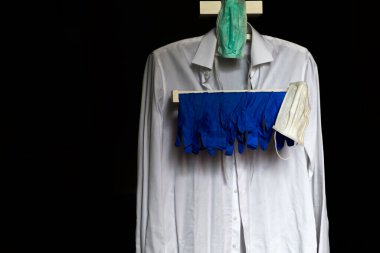 Beyaz gömlekli elbise askısı, mavi eldivenli ve maskeli bu salgında dışarı çıkmak için. Covid19. Siyah arkaplan.