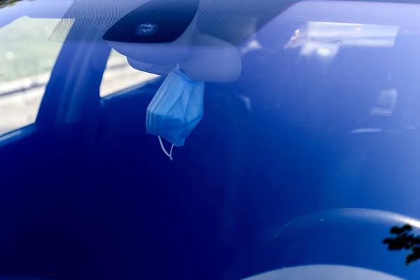 Mask hanging from the inside mirror of a car. It\'s already part of our lives. Selective focus