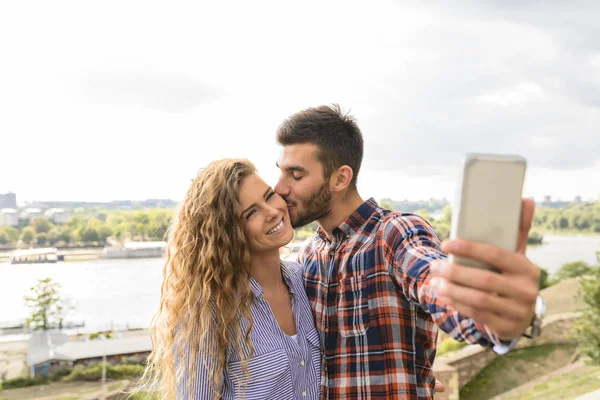 Joven pareja atractiva tomando selfie cerca del río — Foto de Stock