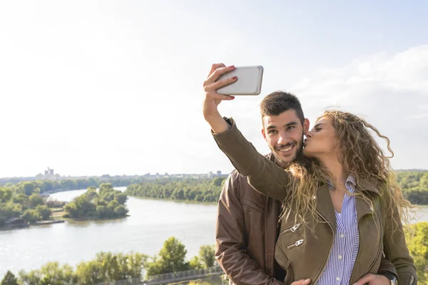 Jovem casal feliz tirando fotos selfie perto do rio — Fotografia de Stock