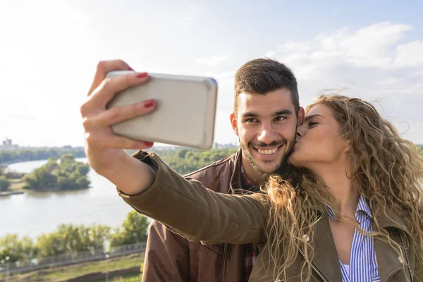 Feliz joven pareja tomando fotos selfies cerca del río — Foto de Stock