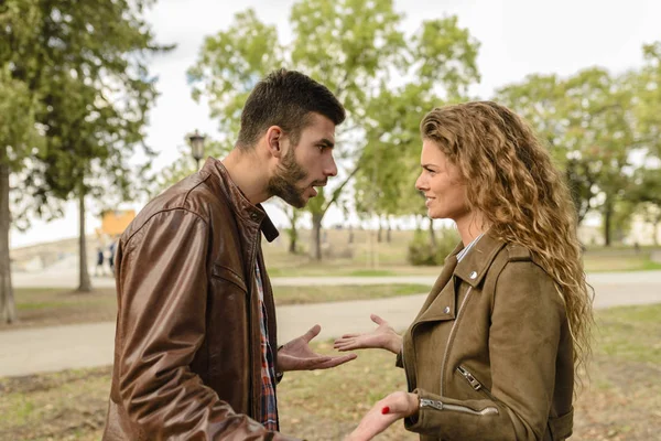 Pareja joven debatiendo en el parque público — Foto de Stock