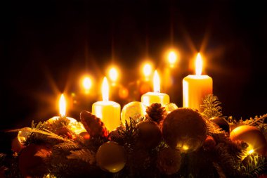 Noel çelengi ve yanan sarı mumlar.