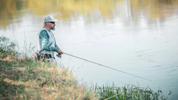 Pescatore con filatura sulla riva del fiume. — Foto Stock