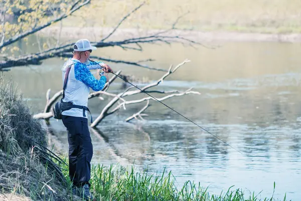Een visser vist met een draaiende hengel op de rivier. — Stockfoto