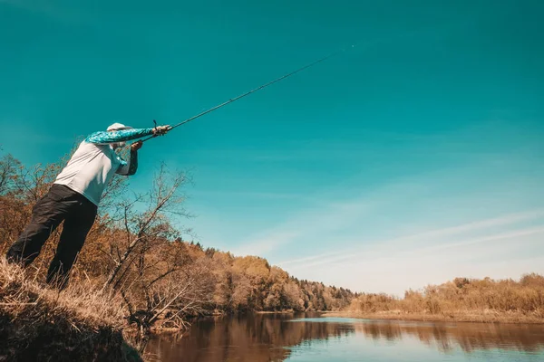 Fischer mit einer Spinnrute, die Fische auf einem Fluss fängt — Stockfoto