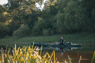 Balıkçı nehirde bir kanoda yüzer..