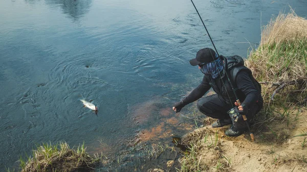 Pescador atrapado un pez en la orilla del río . — Foto de Stock