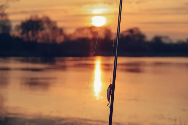 Stav och wobbler på en solnedgång bakgrund. Fiskeredskap. — Stockfoto