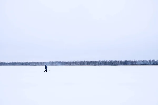Um pescador solitário num lago congelado. Pesca no gelo . — Fotografia de Stock