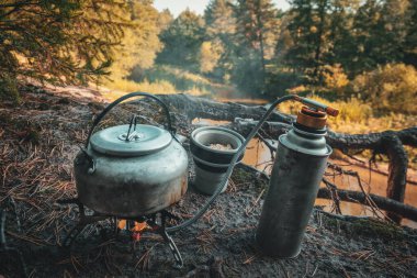 Çaydanlık, gaz ocağı ve silikon bardak yakın çekim. Ormanda yürüyüş..