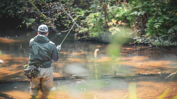 Un pescador atrapa girando en los vadeadores. Pesca de truchas . —  Fotos de Stock