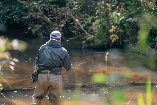 Un pescatore lancia un'esca che gira sullo sfondo di un bellissimo fiume . — Foto Stock