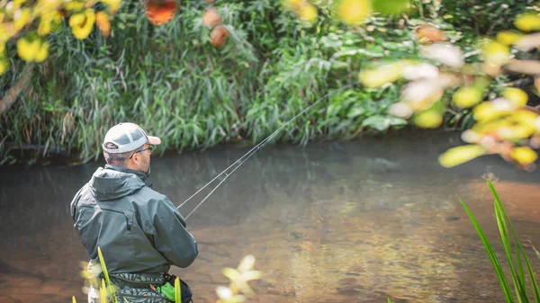 En fiskare snurrar i vadarna. Fiske efter öring. — Stockfoto