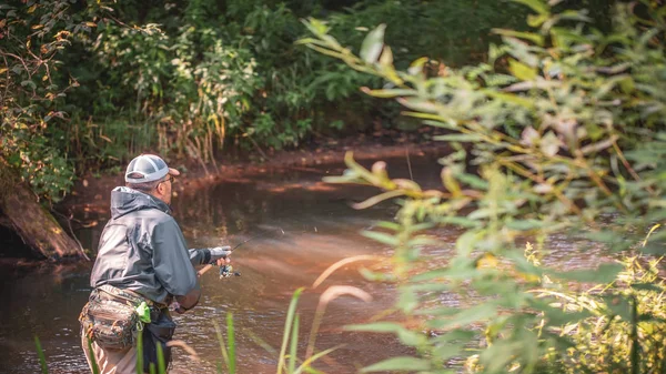 En fiskare snurrar i vadarna. Fiske efter öring. — Stockfoto