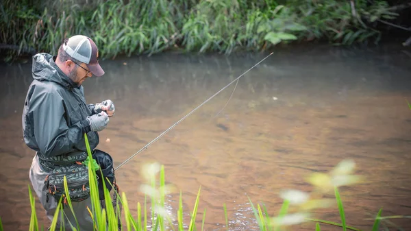 Un pescatore si sorprende a filare nei trampolieri. Pesca alla trota . — Foto Stock