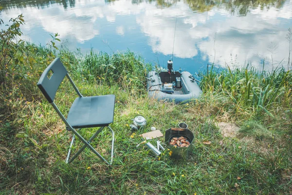 Prepara el almuerzo en la orilla del río. Pesca desde un barco . —  Fotos de Stock