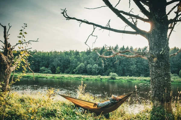 Un homme se repose dans un hamac sur la rive de la rivière . — Photo