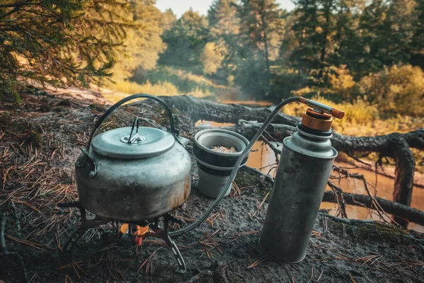 Hervidor, quemador de gas y taza de silicona de cerca. Senderismo en el bosque . —  Fotos de Stock
