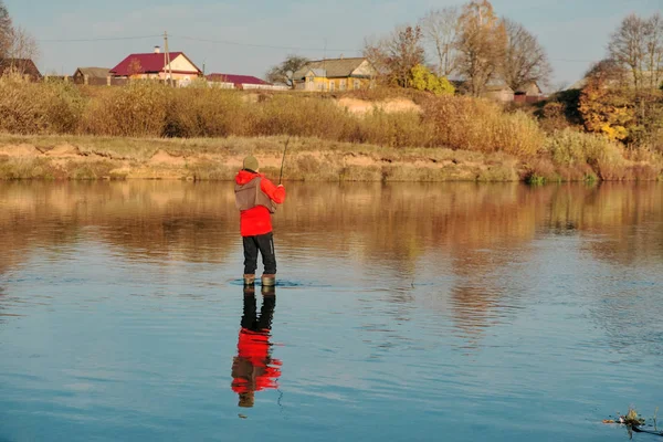 Um pescador está de pé em botas e pesca . — Fotografia de Stock