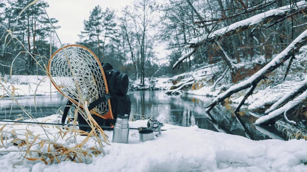 Zaino e attrezzatura da pesca sulla riva del fiume invernale . — Foto Stock