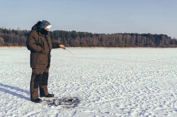 Pesca de Inverno. Pescador no fundo de um lago congelado . — Fotografia de Stock