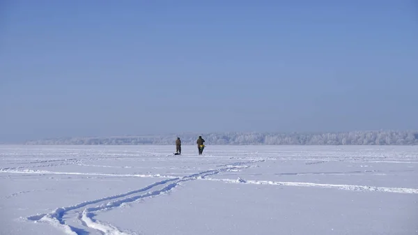 Des pêcheurs marchent le long du lac gelé. Pêche d'hiver . — Photo