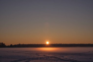 Donmuş bir orman gölünde gün batımı.