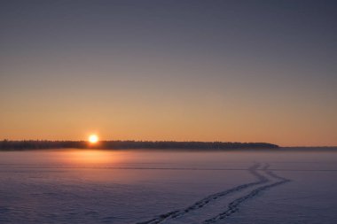 Donmuş bir orman gölünde gün batımı.