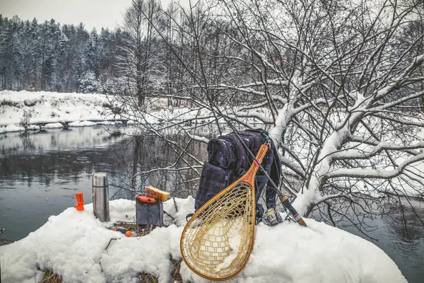 Um piquenique em uma viagem de pesca, em um rio de inverno coberto de neve . — Fotografia de Stock