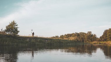 Nehir kıyısındaki bir balıkçının silueti..