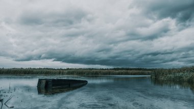 Gölde yalnız bir balıkçı teknesi. Fırtınalı hava.