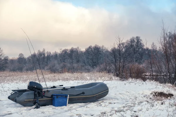 Надувная рыбацкая лодка на берегу зимней реки . — стоковое фото