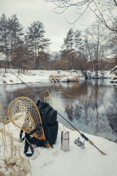 Mochila y aparejos de pesca en la orilla del río de invierno . —  Fotos de Stock