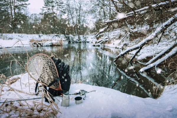Sac à dos et matériel de pêche sur la rive de la rivière d'hiver . — Photo