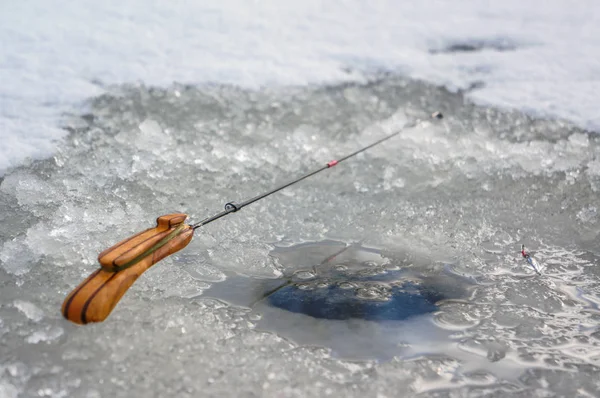 Caña de pescar de invierno y cebo sobre fondo de hielo . — Foto de Stock