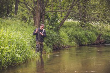 Orman nehrinin kıyısında bir balıkçı..