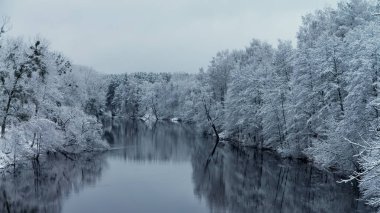 Snow-covered winter river. Fishing with spinning.